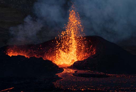 Lava sprutar upp ur en krater och rinner på marken.