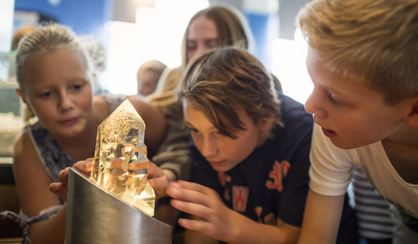Barn undersöker en kristall i utställningen Skatter från jordens inre.