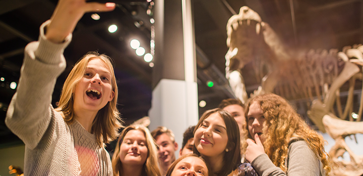 Ungdomar tar selfie framför T-rex i utstälnilngen Fossil och Evolution.
