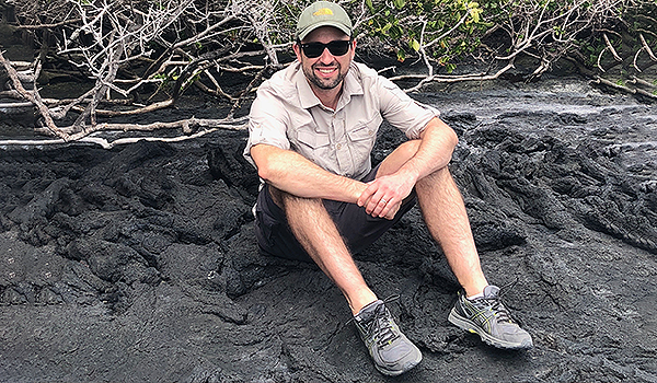 Jonathan Williams, regissör till filmen Oceans, sitter på marken i kortbyxor, solglasögon och keps.