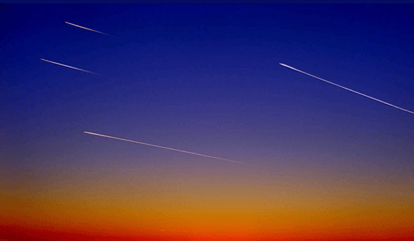 Meteoriter på en blå himmel som skiftar i gult och rött längst ner.
