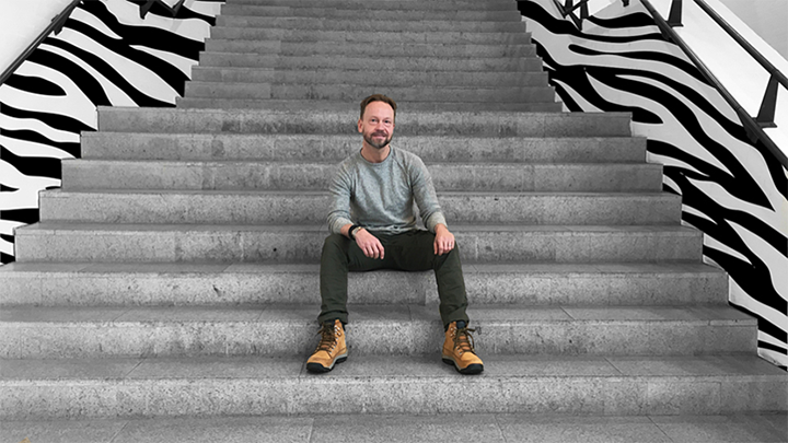 Fotograf Björn Persson sitter i en trappa vars sidor har ett zebramönster.